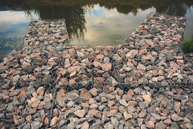 lying stone supported by a metal mesh. Technology of construction of fences from natural materials.