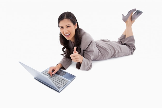 Lying woman with laptop giving thumb up