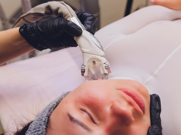 Photo lymphatic drainage massage lpg apparatus process therapist beautician makes a rejuvenating facial massage for the model in a beauty salon close up selective focus