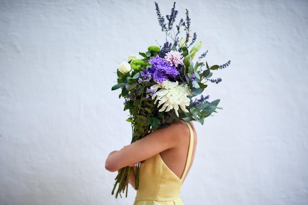 Maak deel uit van de natuur Studio-opname van een onherkenbare vrouw die een boeket bloemen vasthoudt terwijl ze tegen een grijze achtergrond staat