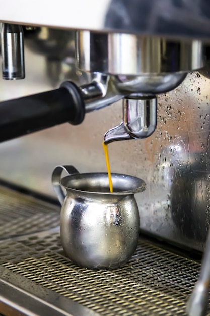 Maak espresso met een koffiemachine. Verse koffie gaat van de machine naar de metalen kan