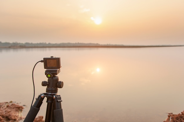 Maak foto's zonsondergang bij de rivier met actiecamera op statief