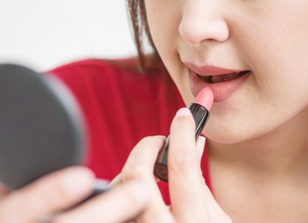 Maakt de Aziatische vrouw van de close-up omhoog door lippenstift in kosmetisch concept