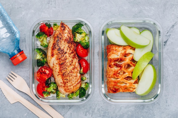 Maaltijdbereidingscontainers voor gegrilde kip met rijstbroccoli en tomaten en desserttaart met groene appel Bovenaanzicht