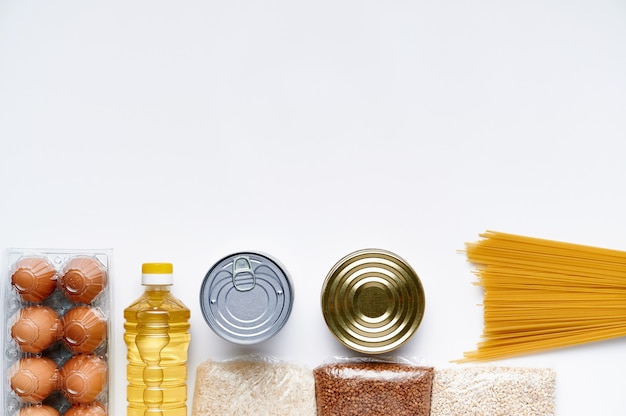 Maaltijdbezorging, donatie. Rauwe granen, granen, pasta en ingeblikt voedsel op een witte tafel.