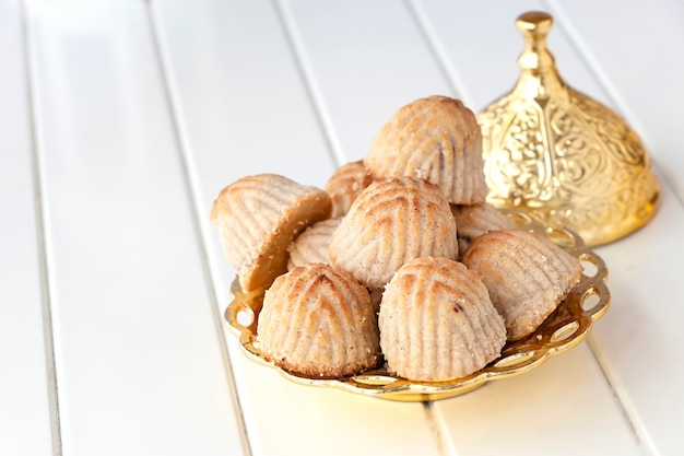 Maamoul traditioneel Arabisch gevuld gebak of koekje met dadels of cashew of walnoot of amandel of pistachenoten. Oosterse snoepjes. Detailopname. Witte houten ruimte.