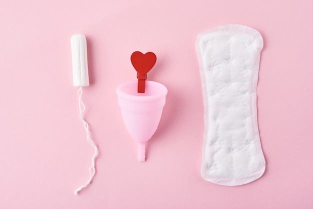 Foto maandverband, menstruatiecup, tampon en rood houten hart