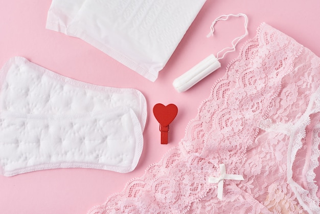 Foto maandverband, menstruatiecup, tampon en slipje op een roze