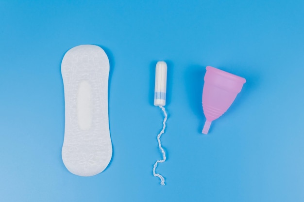 Foto maandverband tampons en menstruatiecup op blauwe achtergrond bovenaanzicht concept van kritieke dagen menstruatie vrouwelijke hygiëne
