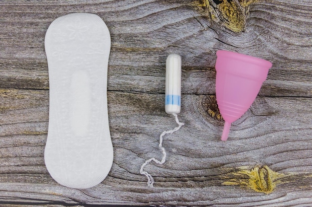 Foto maandverband tampons en menstruatiecup op houten achtergrond bovenaanzicht concept van kritieke dagen menstruatie vrouwelijke hygiëne