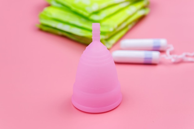 Maandverband tampons en menstruatiecup op roze achtergrond Concept van kritieke dagen menstruatie vrouwelijke hygiëne
