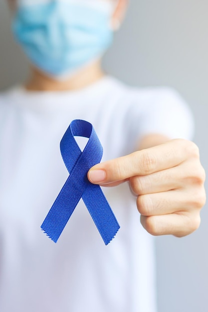 Maart Colorectal Cancer Awareness-maand, vrouw met donkerblauw lint voor het ondersteunen van mensen die leven en ziek zijn. Gezondheidszorg, hoop en Wereldkankerdagconcept