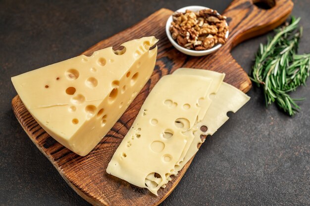 Maasdam cheese with walnut and rosemary on stone table