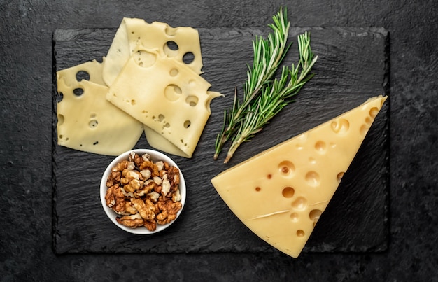 Maasdam cheese with walnut and rosemary on stone table