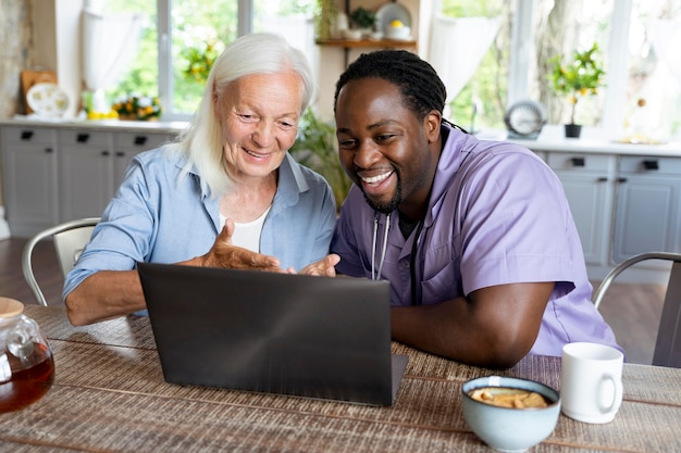 Foto maatschappelijk werker die op een laptop kijkt met een oudere vrouw