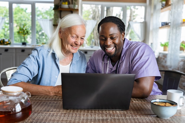 Foto maatschappelijk werker die op een laptop kijkt met een oudere vrouw