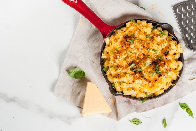 Mac en kaas, macaroni-pasta in amerikaanse stijl met kaasachtige saus en knapperige paneermeel topping, in geportioneerde pan, wit marmeren tafel, kopie ruimte bovenaanzicht