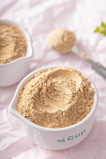 Photo maca powder in measuring cups and a spoon