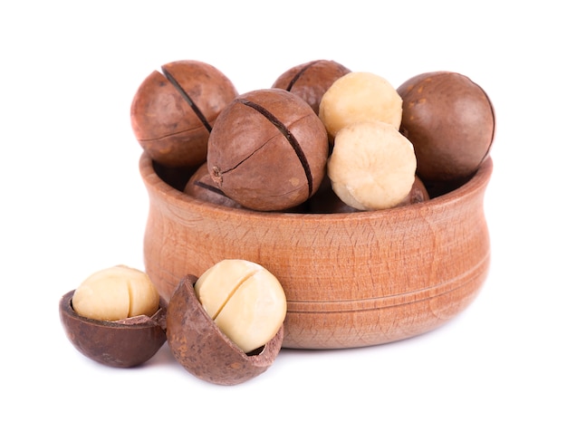 Macadamia noten in houten plaat, die op wit wordt geïsoleerd. Geschilde en ongedopte macadamia.