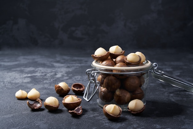 Macadamia nuts in an open glass jar on black  , close-up.