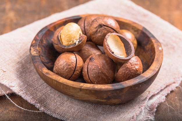 macadamia nuts pile with shells in bag on wooden table