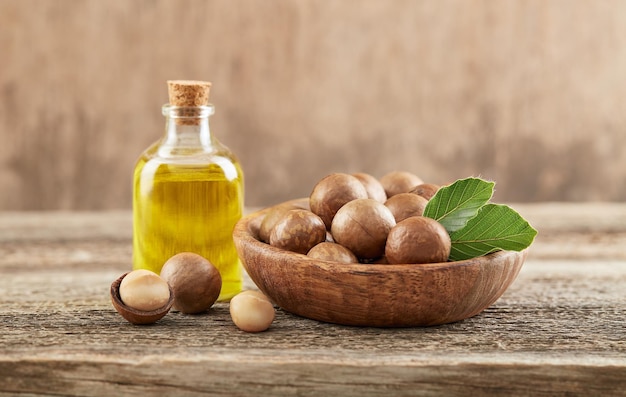 Photo macadamia nuts with oil on old wooden background