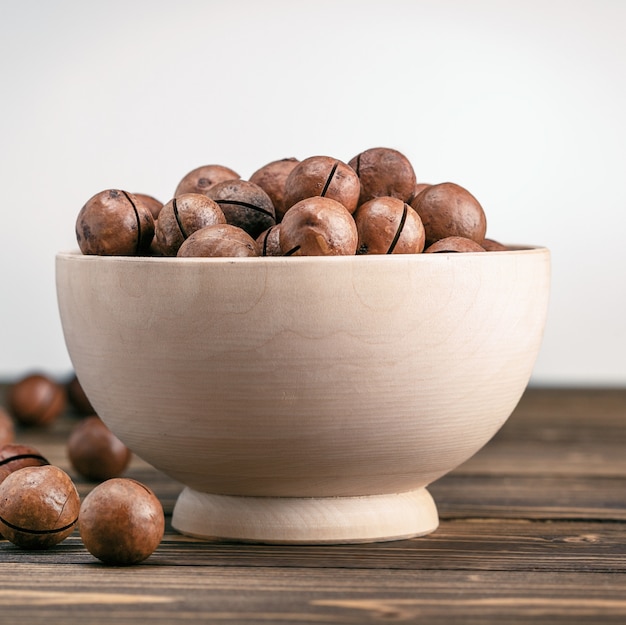Macadamia nuts in a wooden bowl on a brown table.