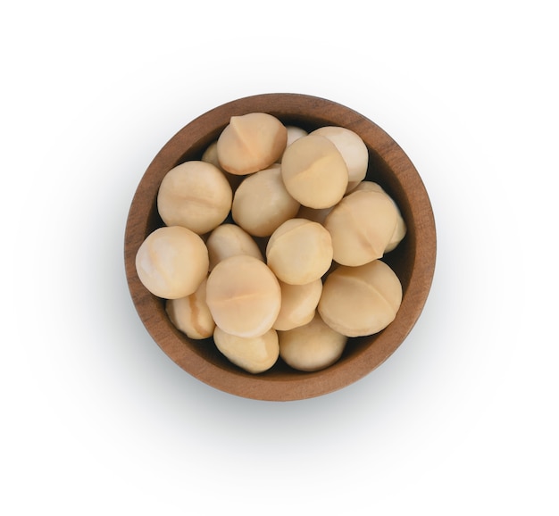 Macadamia nuts in wooden bowl top view isolated