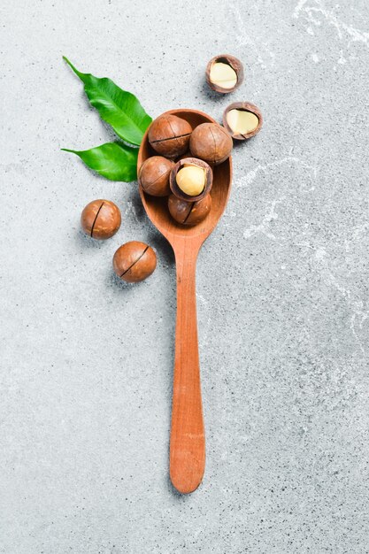 Macadamia nuts in a wooden spoon on a light concrete background Healthy snacks Nuts