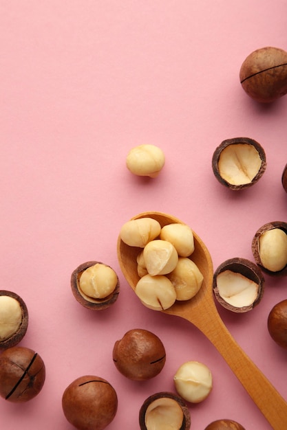 Macadamia in wooden spoon on pink background. favorite for snack and very delicious.have a lot of unsaturated fatty acid. healthy food concept. top view