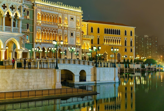 Macao, China - 8 maart 2016: Waterfront en Venetiaans Macau Casino en Hotel, luxeresort in Macao, China. Mensen op de achtergrond. Laat in de avond. Gouden licht verlichting