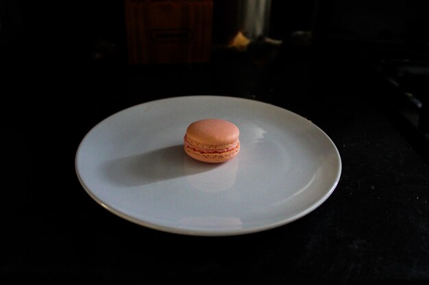 Photo a macaron sits on a white plate in the dark