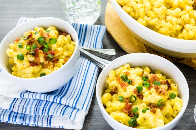 Foto maccheroni e formaggio guarniti con pezzetti di pancetta ed erba cipollina.