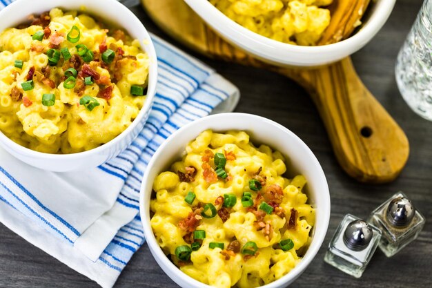 Maccheroni e formaggio guarniti con pezzetti di pancetta ed erba cipollina.