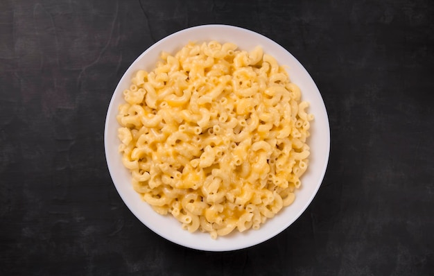 Macaroni and cheese on a white plate on a black background