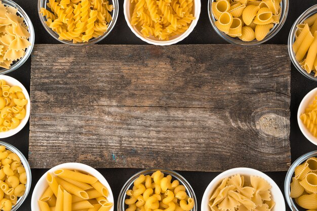 Macaroni of different types on a wooden background.