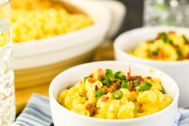 Macaroni en kaas gegarneerd met spekjes en bieslook.