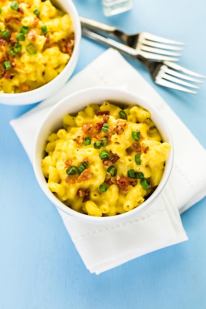 Macaroni en kaas gegarneerd met spekjes en bieslook.