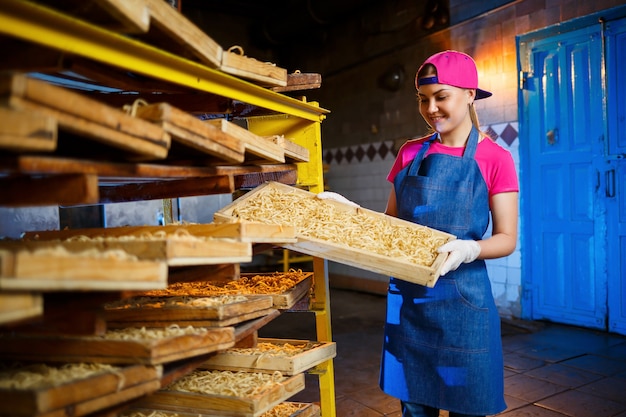 Macaroni factory. Spaghetti production. Raw pasta. Worker with a box of pasta. Girl works in the production of pasta