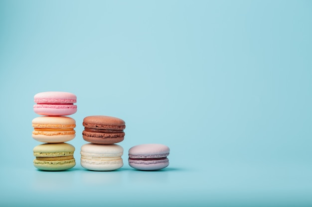 Macaroni-koekjes van verschillende kleuren zijn gerangschikt in de vorm van piramidestappen op een blauwe achtergrond.