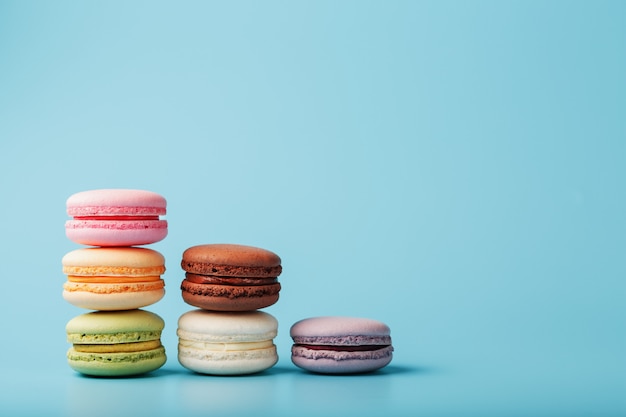 Macaroni-koekjes van verschillende kleuren zijn gerangschikt in de vorm van piramidestappen op een blauwe achtergrond.