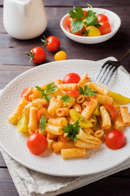 Maccheroni, pasta in salsa di pomodoro e formaggio in un piatto su un tavolo di legno