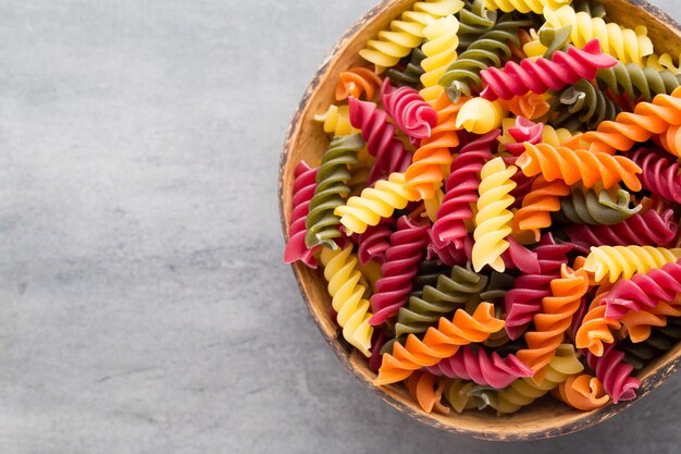 Macaroni pasta in a wooden bowl on a gray background.