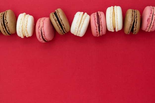 Macarons cakes over red background. Flat lay. Copy space.