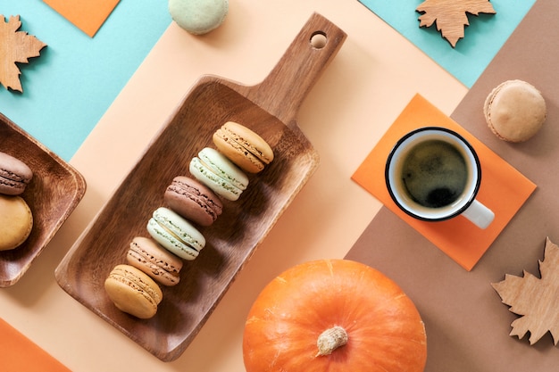 Macarons en espresso, plat op geometrische papiermuur met herfstdecoraties