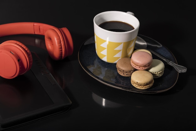 Macarons with coffee cup and technology on a black background