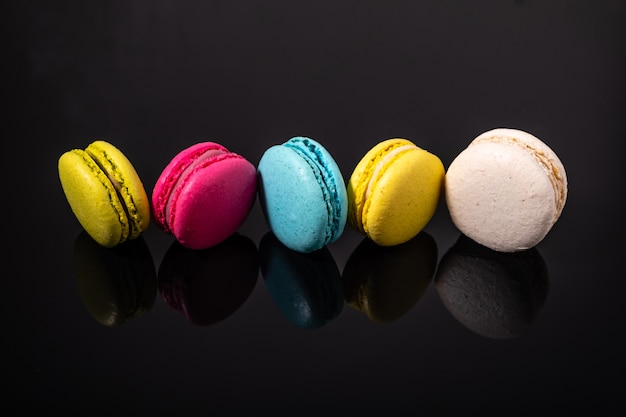 Macarons на деревянном столе на черном.