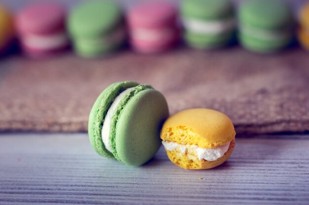 Macaroons are laid by a line with one green and yellow biten off macaroon in the centre of picture