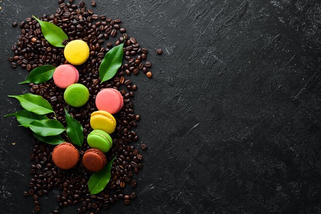 Macaroons colored cakes On a black stone background Top view Free space for your text