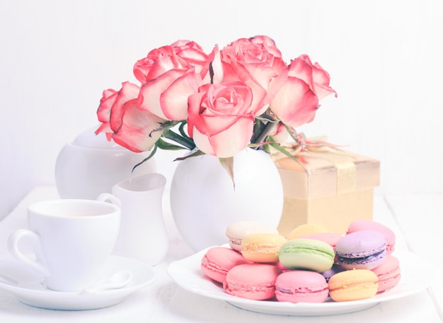 Macaroons in gift box and roses in vase